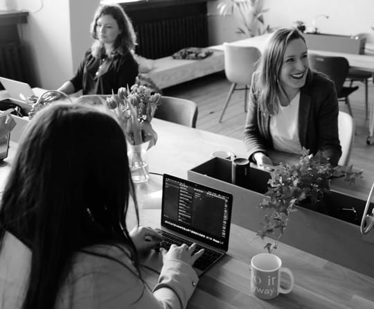 two women sitting at desk and working together